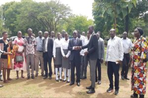 Justice Byabakama greets one of the students during a photo moment with Mvara S.S student leaders shortly after the meeting