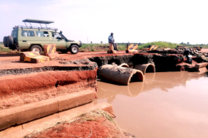 A man looks on as a vehicle drives tourists past the floodprone section of the road on Tuesday. Photo Credit_ Andrew Cohen Amvesi