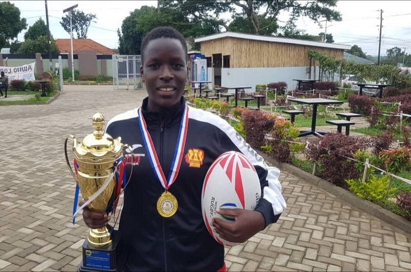 Olive Onyiru posses for a photo with her medal and one of the trophies won. Photo Credit Andrew Cohen Amvesi