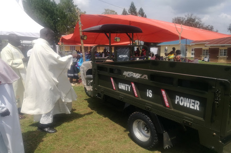 Monsignor Adeti blesses the newly bought tri-cycle by sprinkling water on it on Saturday. Photo Credit_Andrew Cohen Amvesi