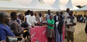 MP Oguzu (in white Nigerian wear) prepares to handover a mattress to Faida Precious as her parents (R) and leaders looked on