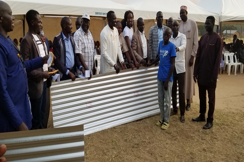 One of the talented boys receives part of the share of his ironsheets from MP Oguzu on Wednesday