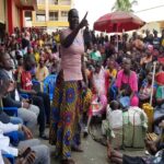 Loice Kazuba speaking to her members as local leaders (seated L) looked on during the fishmongers' meeting
