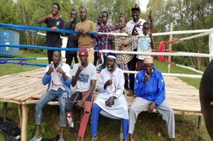 Some of the reformed ghetto children possing for a group photo with Osino (seated 2R) and coaches on a stage prepared for the boxing show