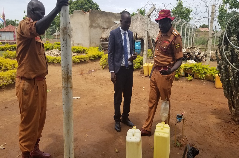 Alidro (R) shows Arima the NWSC water point inside the prisons. Photo Credit Andrew Cohen Amvesi