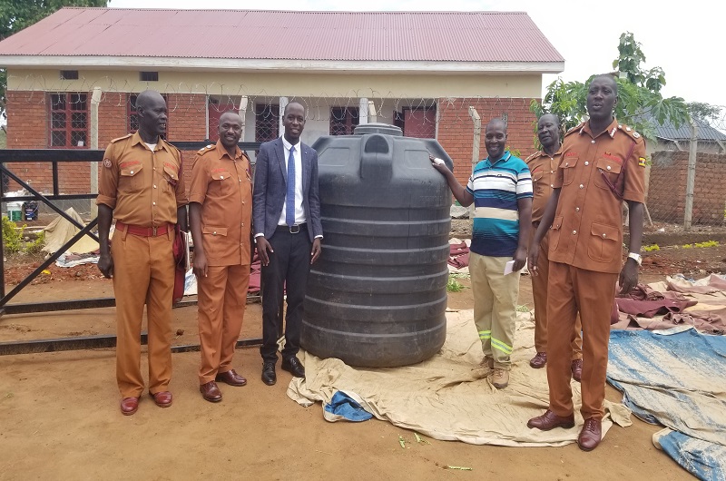 Prison officers join Arima (3L) in a group photo after receiving the water tank (C) at Yumbe government prison on Monday. Photo Credit Andrew Cohen Amvesi