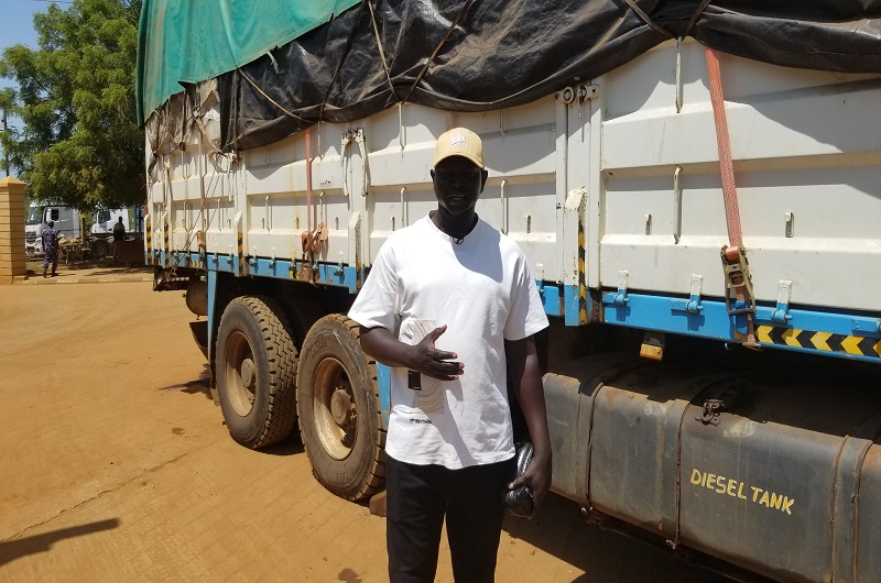Tonny speaking next to one of his fish trucks at Elegu on Wednesday