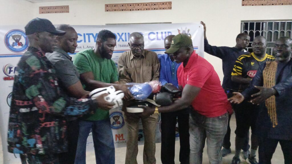 Andama Daku (in green) handing over the assorted boxing materials to Arua City Boxing Club