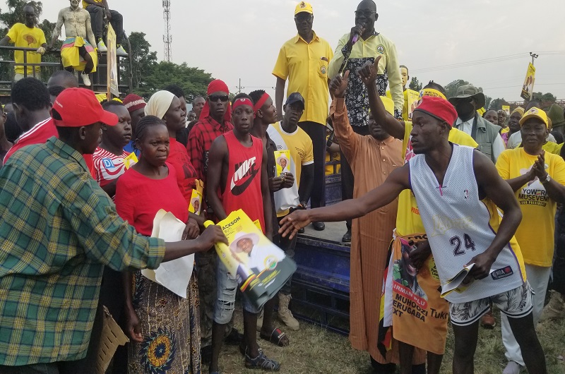 Andama hands over President Museveni's posters to some of his team members who crossed to NRM on Friday. Photo Credit, Andrew Cohen Amvesi