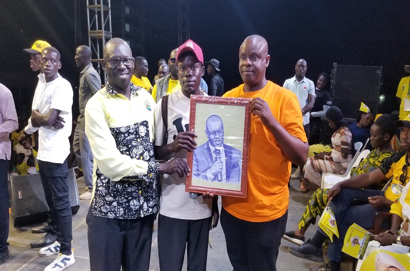 A youth in Arua Central Division hands over Balaam's portrait he made as a gift to the Minister on Monday. Photo Credit, Andrew Cohen Amvesi