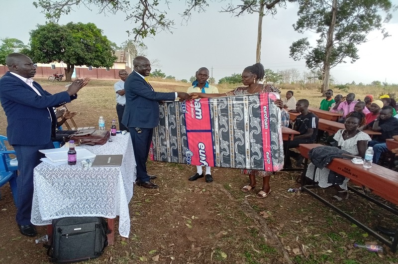 Banya shakes hands with a parent while donating a mattress to her child on Thursday. Photo Credit; Andrew Cohen Amvesi