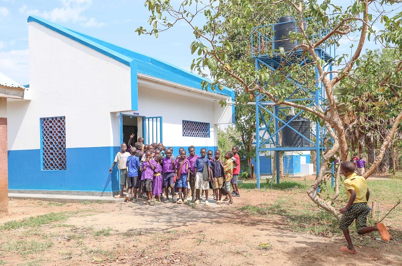 Pupils rushed to gather for a group photo at a new toilet facility constructed at their school
