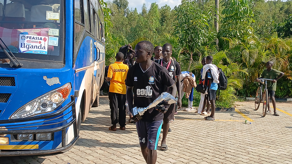 A player coming out with the trophy from the bus on their arrival at Oasis Campus Muni. Photo by Matata Benzamin
