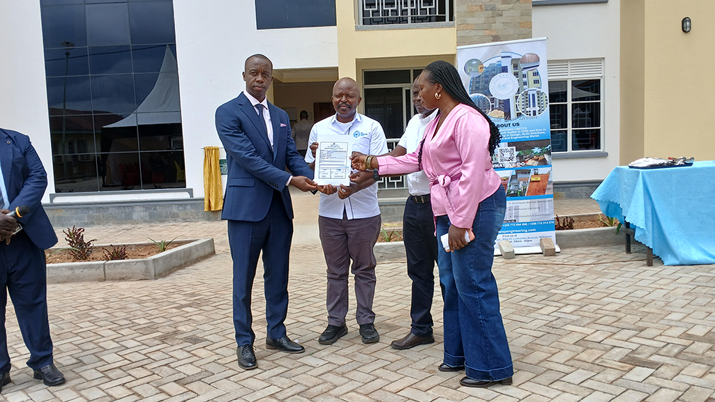 Minister of State for Health in charge of Primary Health Care, Dr. Charles Ayume, handing over certificate to the contractor for completion of the project. Photo by Matata Benzamin