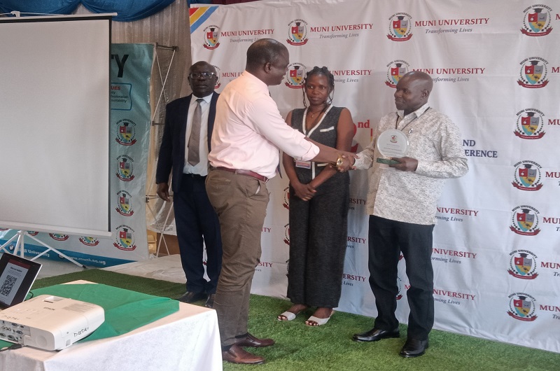 Assoc. Prof. Denis Atibuni prepares to receive his accolade from Dr. Kibirai for being the over all best presenter during the conference