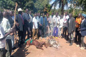 The aggrieved rival Lugbara Kari members gather around fire with one elder lying on the ground during their meeting in Onduparaka on Saturday
